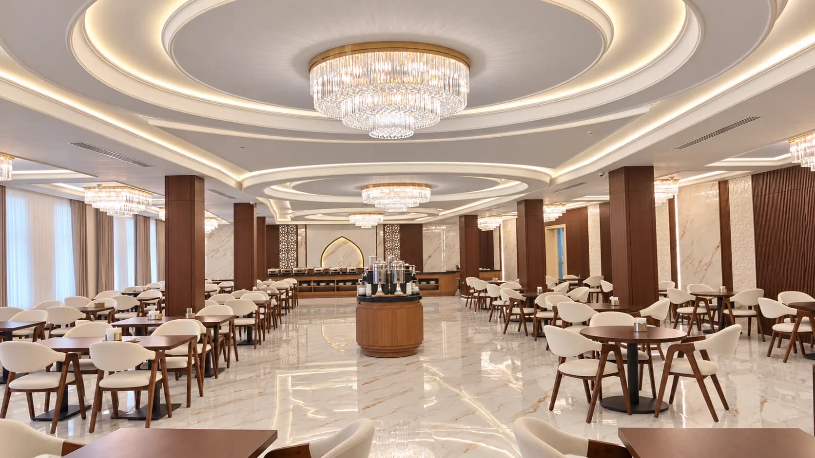 Saji Nusantara dining room with chandeliers, patterned ceilings, and set tables.